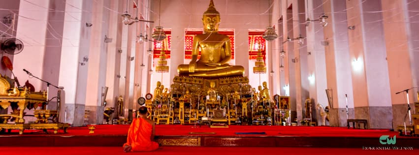 Un pratiquant bouddhiste en méditation devant l'image principale du Bouddha à Wat Mahathat