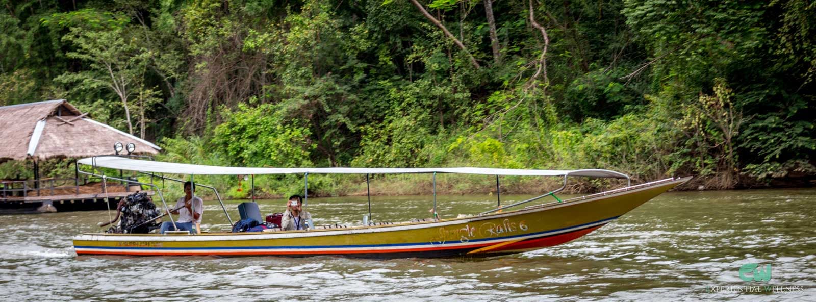 Ein Longtail-Boot fährt durch den Fluss in Kanchanaburi