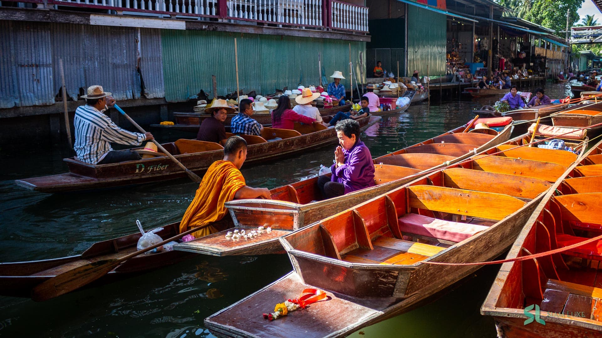 Einheimische erhalten den Segen eines buddhistischen Mönchs auf einem Boot am schwimmenden Markt Damnoen Saduak